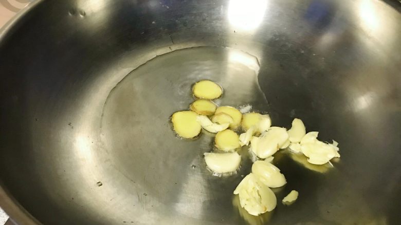 芸豆烧肉,油锅烧热,爆香姜片和蒜瓣。