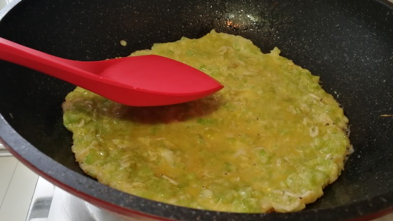 快手早餐&香芹小虾米鸡蛋饼,把锅用手端离火苗,要用锅铲把蛋液顺时针铲平整,别煎糊了。