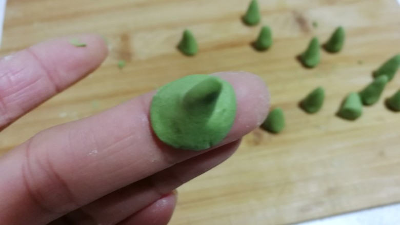 南瓜豆沙小汤圆,再把底部捏薄,凹成一个图钉形状,抹点水沾在南瓜汤圆团上