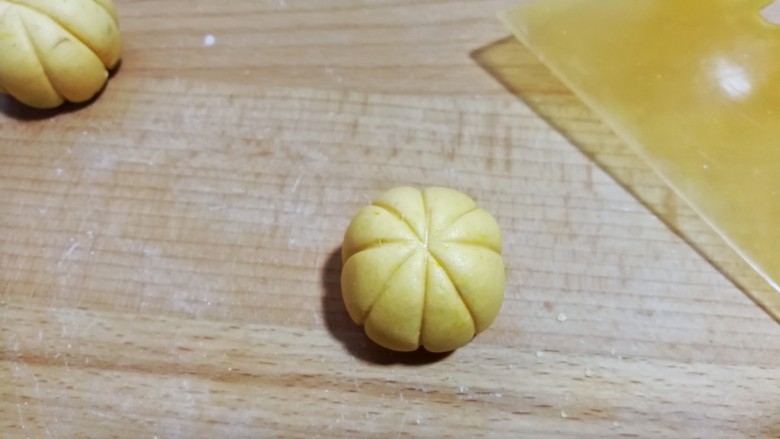南瓜豆沙小汤圆,然后用刮板呈“米”字形,在糯米团上压出南瓜形花纹(操作时左手拿糯米团,右手拿刮板从上往下轻轻推挤着压出花纹,一个人拍照不好拍出此步骤细节)