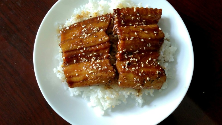 鳗鱼饭,盘子里盛适量白米饭，浇上一些鳗鱼酱汁，把鳗鱼铺上，撒上一些白<a style='color:red;display:inline-block;' href='/shicai/ 666'>芝麻</a>，就可以开吃了