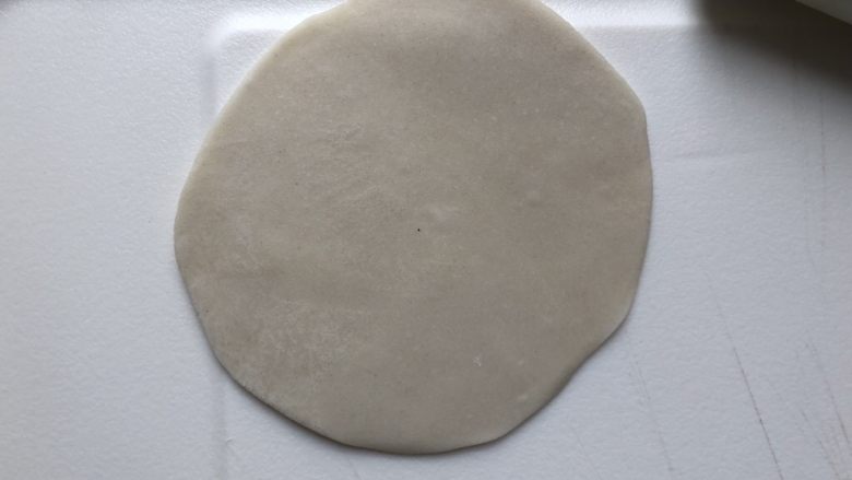 烫面春饼,取一个面团,按扁,用擀面杖擀成稍大的饺子皮大小