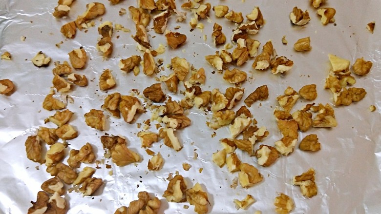 不一样的核桃桃酥,核桃仁掰成小块放入铺了锡纸的烤盘,170°烤5分钟
