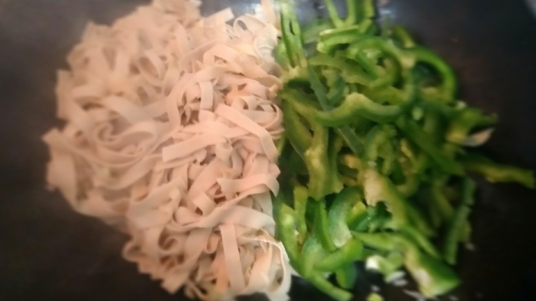 充满爱的青椒豆皮,豆皮五分热时,再放入青椒。(青椒加热时会破坏维生素,所以时间要短。)