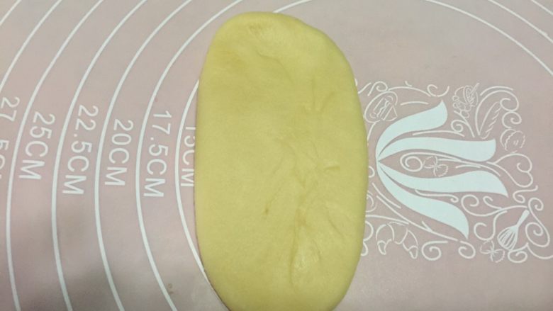 香蕉酥,取一块面团,收口朝上,用手指在中间轻按一下,然后用擀面杖从中间往上擀一下再往下擀一下成牛舌状,动作要干净利落,尽量不要多次擀压