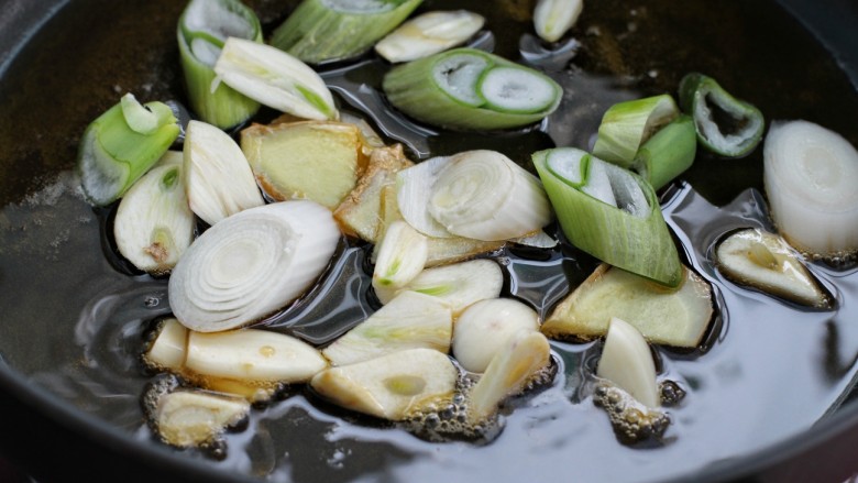 东北榛蘑炖鸡腿,锅中放适量食用油烧至五成热,炒香葱段和姜、蒜片
