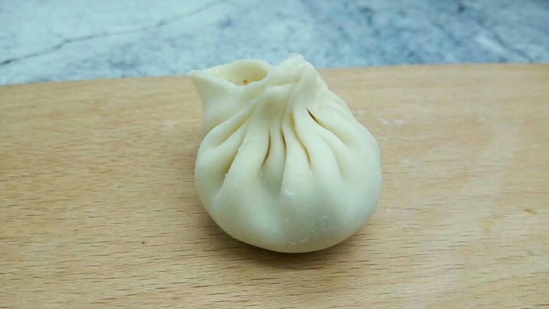生煎包《饺子皮版》,左手的食指把旁边的面皮推向右手食指的位置,形成一个褶子的形状,捏完最后一个褶,