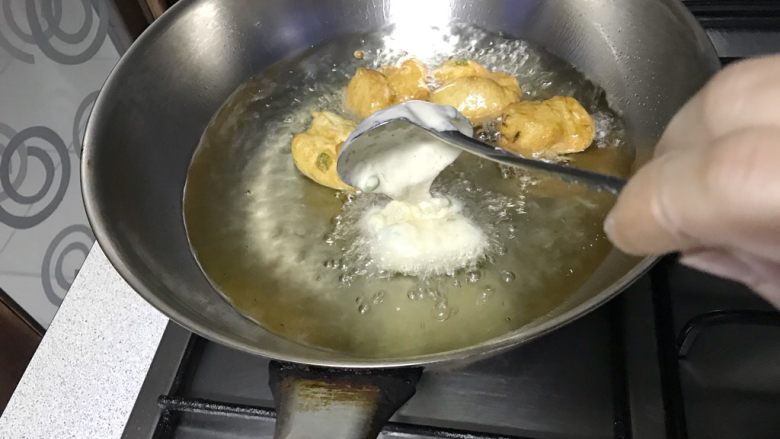 炸面团子,将面糊一股脑的在同一个位置,不要移动勺子,倒入油锅里。