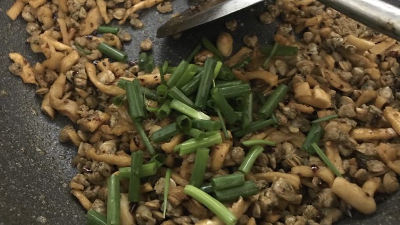 萝卜干炒蚬肉(麻辣风味),炒香后放入葱花,翻炒几下就可以装碟了。