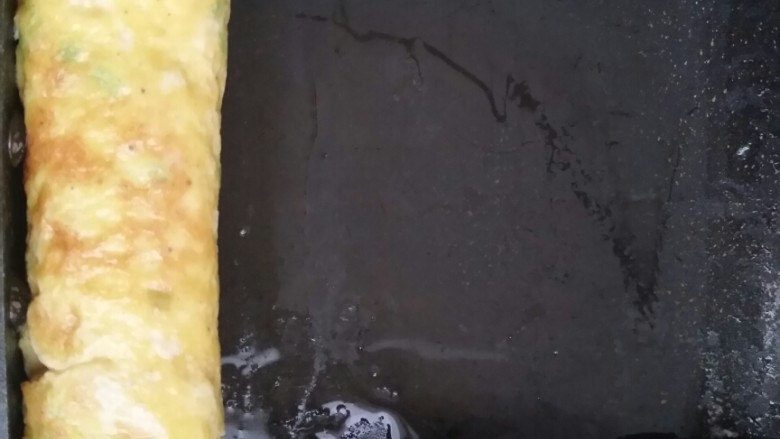 超简单的火腿厚蛋烧,将卷好鸡蛋放到一端。