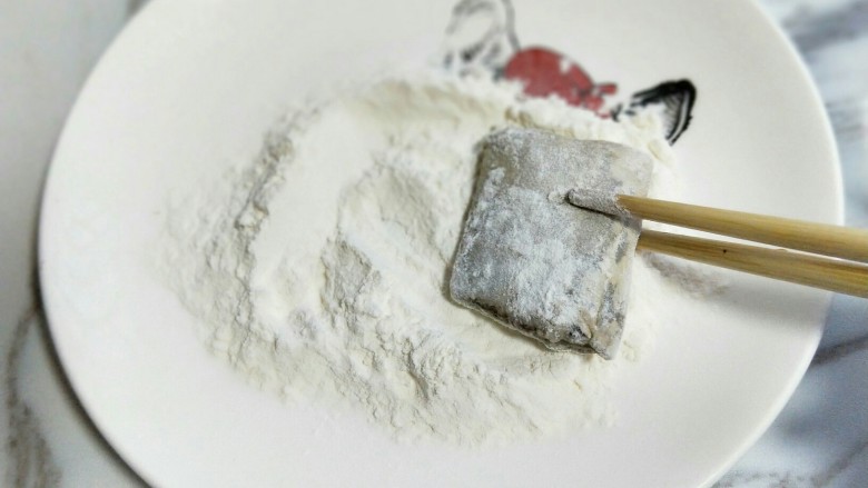 香煎不腥不碎的黄金带鱼,腌制好的带鱼,用筷子夹着沾满面粉。