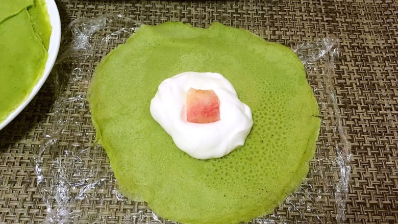 抹茶班戟,在面片中间放入适量的淡奶油跟水果块,本来准备放芒果的,结果发现芒果坏了,就用了甜桃