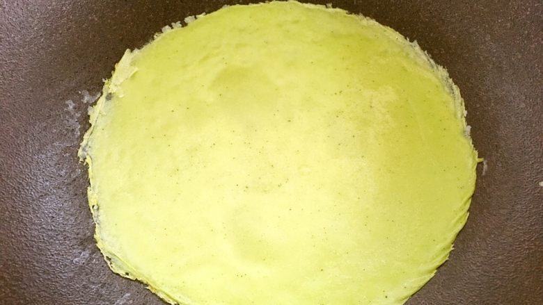 抹茶班戟,平底不粘锅小火加热,有一点温度即可,抹上一点点黄油,倒入适量的面糊,摇晃平底锅,让面糊流动成薄薄的一层圆形,面糊凝固即可,用刮棒轻轻铲起来,放到盘子内,之后再摸一点点黄油,再摊第二张