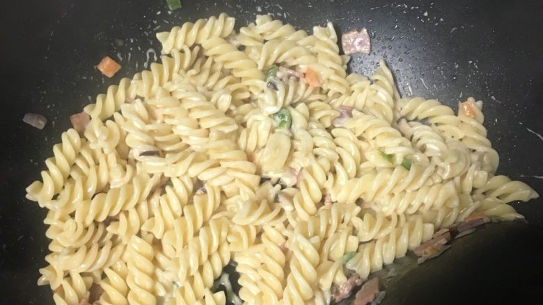 奶油培根螺旋意大利面,放入奶油,小火继续翻炒,撒点黑胡椒
