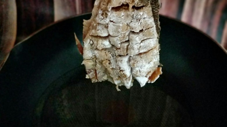 松鼠鲈鱼,这样,首先拎着鱼尾巴,将热油用勺子往鱼身上淋,这样鱼更容易定型。
