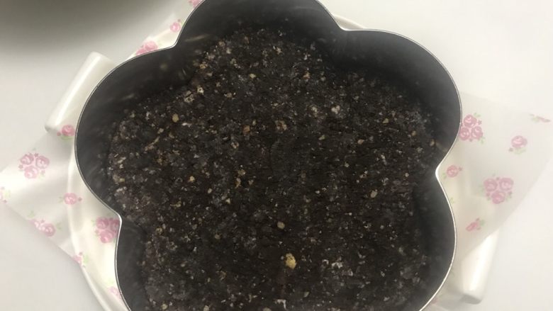 巧克力乳酪双享慕斯,慕斯圈底部垫油纸,把饼干底均匀的铺在底部,用勺子压平压紧,然后入冰箱冷藏备用。