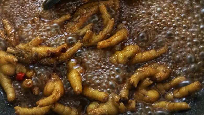 红焖啤酒鸡爪(香辣风味),鸡爪焖到这样的汁水量,转大火收汁,要不停翻炒。