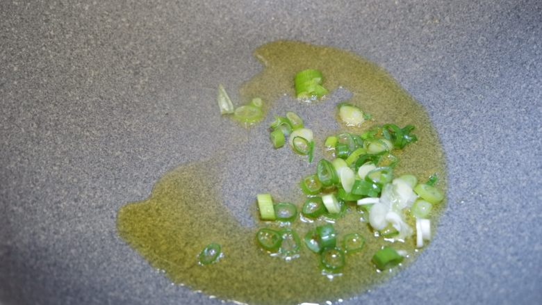 儿童食谱—鸡刨豆腐,锅里倒油烧热,先将一半的葱花放入锅内,炒出香味,