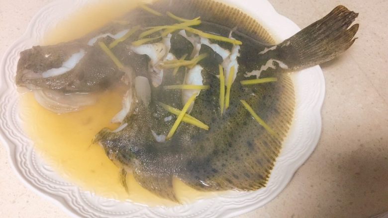 清蒸多宝鱼,拿出鱼盘,控去多余水分,捡出姜丝