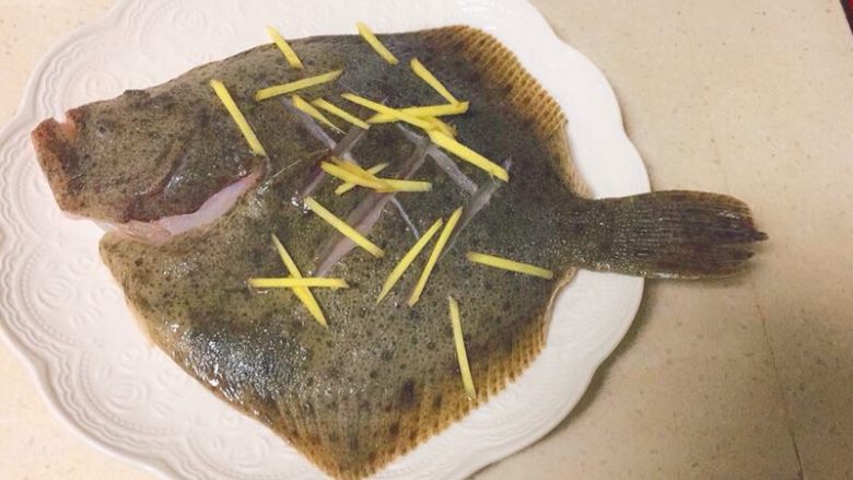 清蒸多宝鱼,用厨房纸吸干多余水分,放上姜丝少许盐腌制10分钟