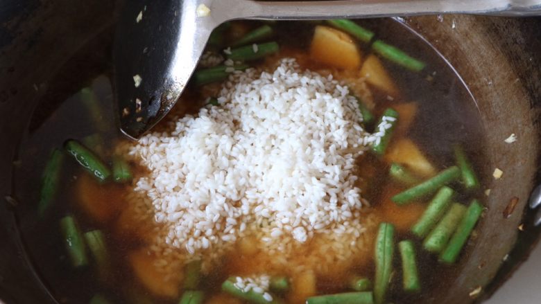 土豆豆角焖饭,最后放入大米,大火烧开转小火,焖15分钟左右即可;