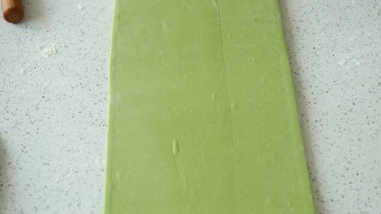 抹茶/原味蝴蝶酥,面片表面在撒一层面粉防粘,将其轻轻擀长,擀的时候用力要均匀,由中间往上下擀到20cm宽,将面片旋转90度,再由中间往上下擀到50cm。擀的时候,由中心向四角的方向擀,容易擀成规则的长方形(图中是配方双倍的量,所以面片擀的比较长)