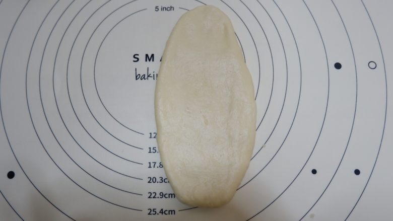叶子椰蓉面包,取一个包好馅料的面团,擀开呈牛舌状。