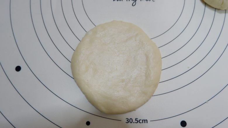 椰蓉花朵面包,收口向下，用擀面杖擀大擀薄一点。擀好放在烤盘上。