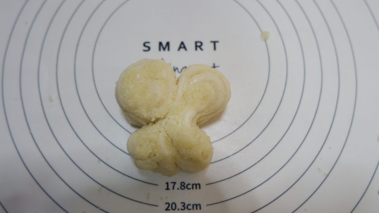 椰蓉蝴蝶面包,用两手食指在下方三分之一处,向里挤压,捏出蝴蝶的形状。