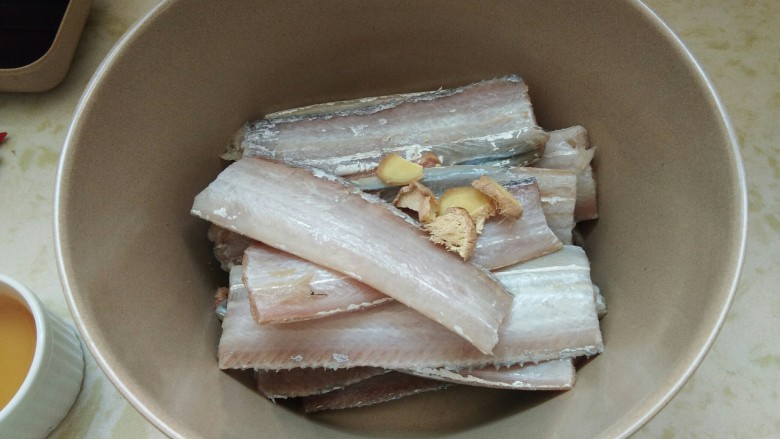 酒香煎带鱼,找一个干净无水无油的大碗,把一盘<a style='color:red;display:inline-block;' href='/shicai/ 386'>带鱼</a>放里面然后下入姜片。