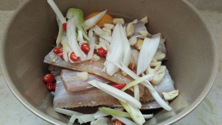 酒香煎带鱼,下入葱丝,蒜末,泰椒段。