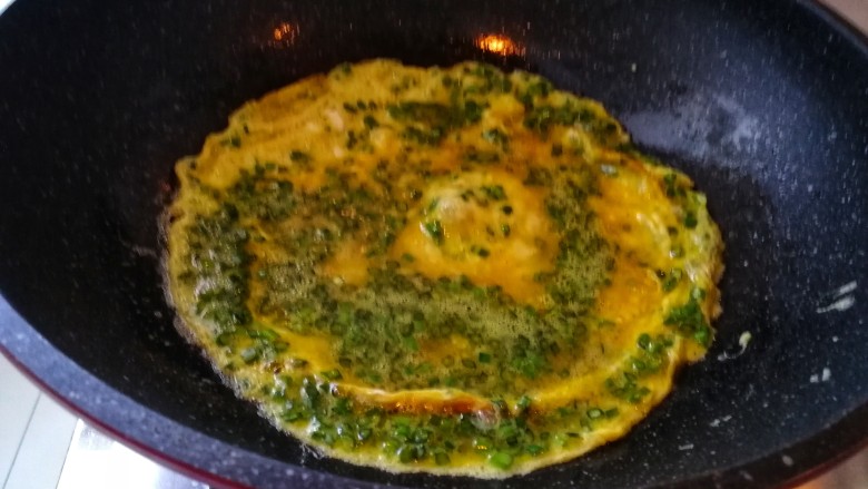 快手早餐之韭苔鸡蛋饼,开始煎鸡蛋饼:要端着锅用锅铲慢慢把蛋液弄平整,不要煎糊了。