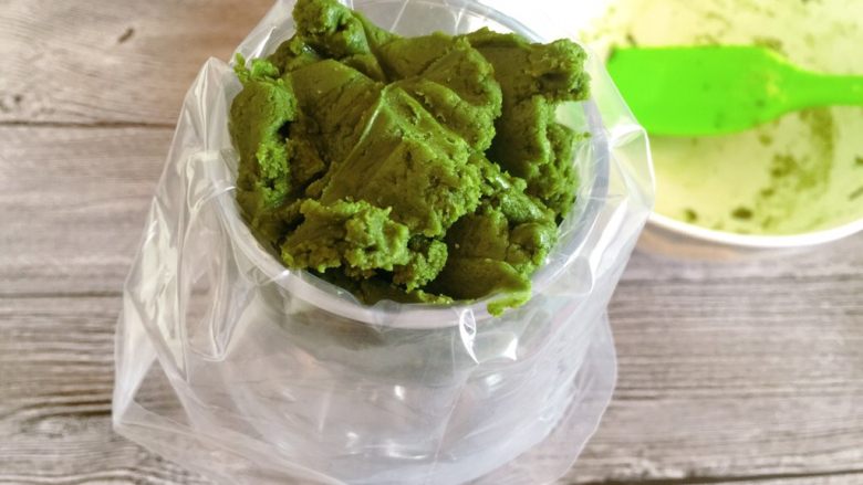 抹茶曲奇饼,找一个杯子,套好裱花袋,把混合好的面团装入裱花袋中。