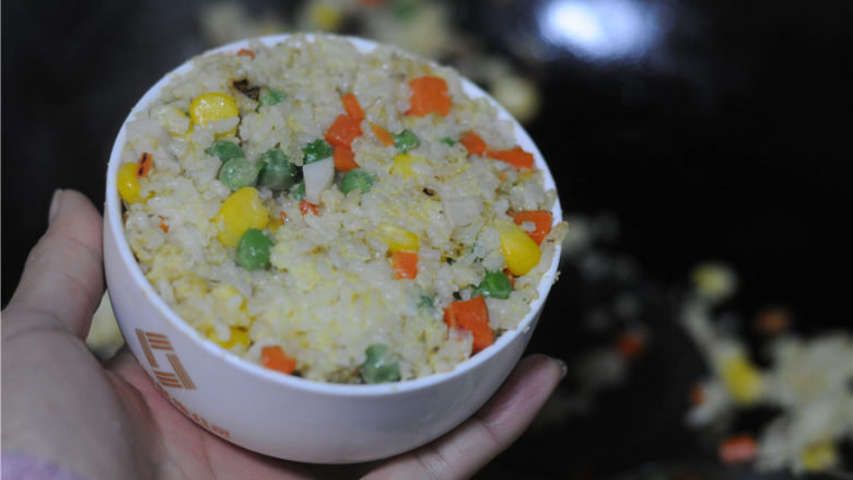 香菇酱黄金蛋炒饭,将炒好的米饭盛入碗里,用锅铲边装边按紧实