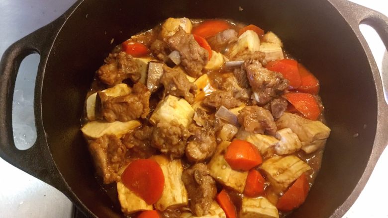 铸铁锅豆腐焖排骨,小心地把排骨捡到表面上来,把豆腐没入汤汁中继续焖烧5分钟。关火,别揭盖。