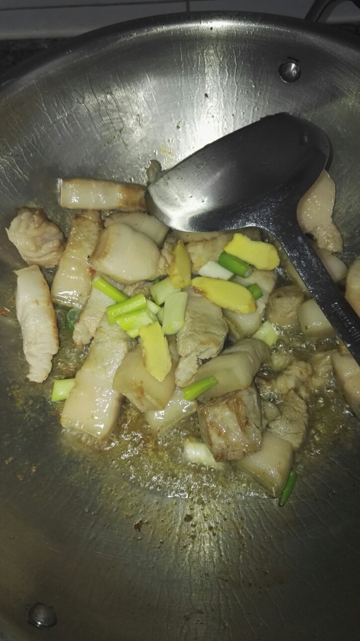 家常砂锅南乳肉,加入姜片,葱段,<a style='color:red;display:inline-block;' href='/shicai/ 718'>料酒</a>适量,继续煸炒。