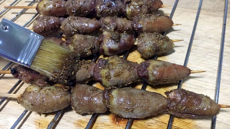 孜然烤鸡心串,鸡心串烤10分钟后取出来,逐个将鸡心串刷上调好的孜然汁。