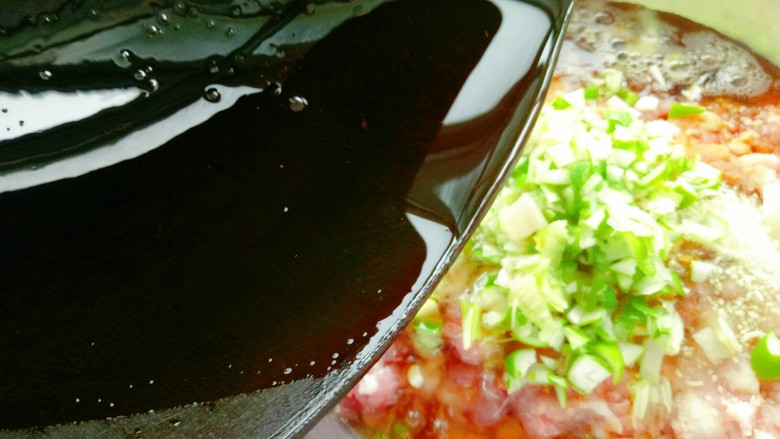 韭菜鲜肉大包子,在馅料盆中放入葱花,然后将刚炸好的油淋在葱花上