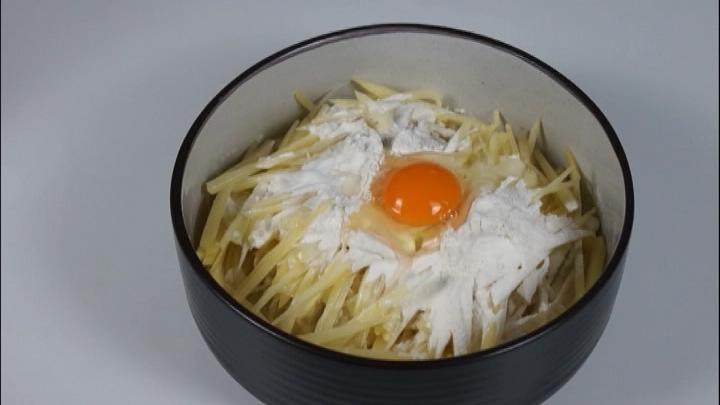 酥脆爽口的香煎土豆饼,做法却如此简单易学!,往土豆丝里倒入等量的面粉、适量盐、打入一个鸡蛋、适量清水搅拌均匀成糊状。