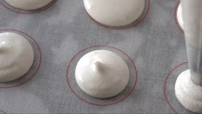 意式抹茶马卡龙,将面糊装入裱花袋(用的圆形裱花嘴),在硅胶垫或烘焙纸上挤出稍厚的圆形(直径2.5cm左右),小心的用牙签挑破表面的小气泡