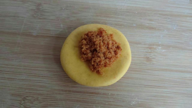 菠萝肉松包,和好的面团不用发酵直接做造型。把南瓜面团分成45克一个的小面团,压扁后放上<a style='color:red;display:inline-block;' href='/shicai/ 432'>肉松</a>。