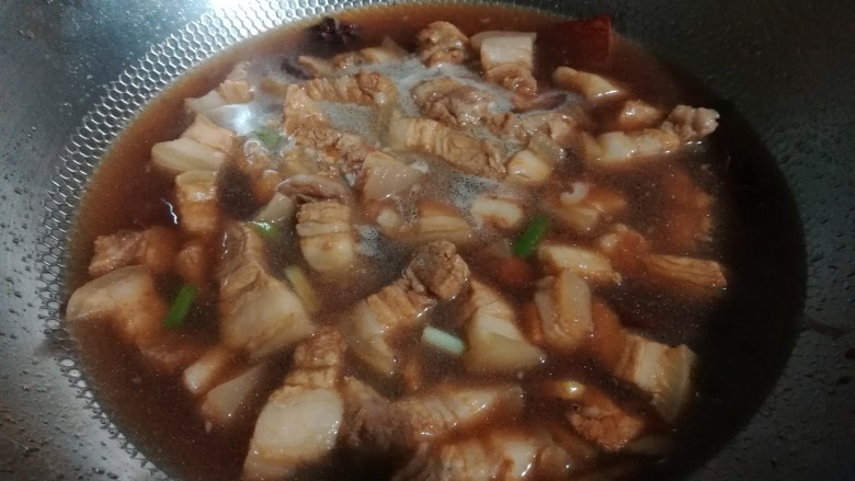 兰花干焖肉,翻炒一两分钟后加入热水。水量没过肉块。煮沸后,盖上锅盖,以小火焖烧。