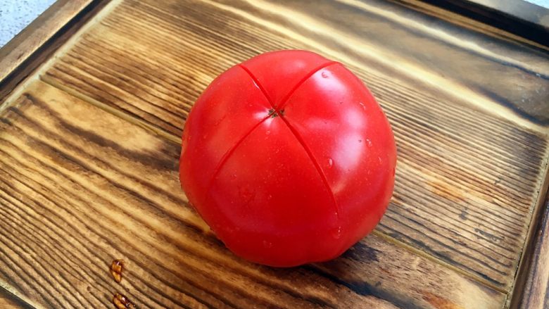 宝宝餐 番茄丝瓜补钙粥,<a style='color:red;display:inline-block;' href='/shicai/ 59'>番茄</a>清洗干净,在顶部划一个十字。