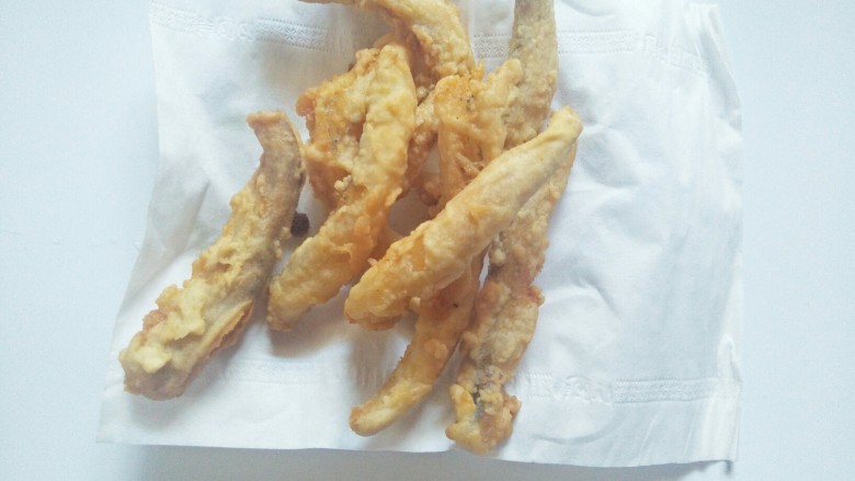 香酥龙头鱼,盘子上披上面巾纸,再把炸好的鱼放上面吸掉多余的油