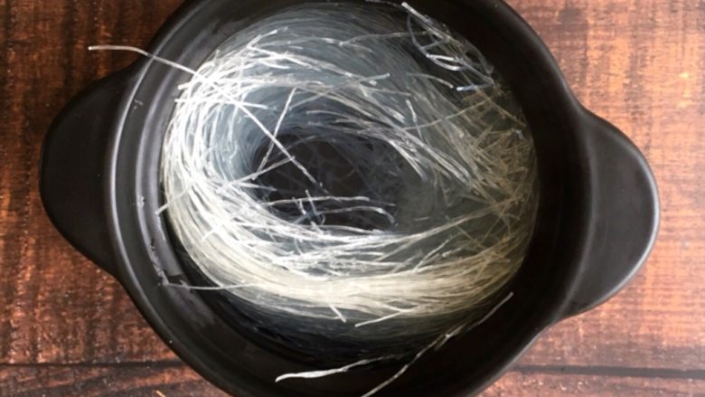 早餐系列之酸豆角肉末粉丝,准备一个煲，里放入粉丝，倒入开水浸泡