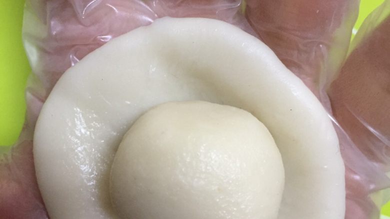 零失败蛋黄酥,取一个油皮用手掌按压,放入油酥,虎口收紧滚圆