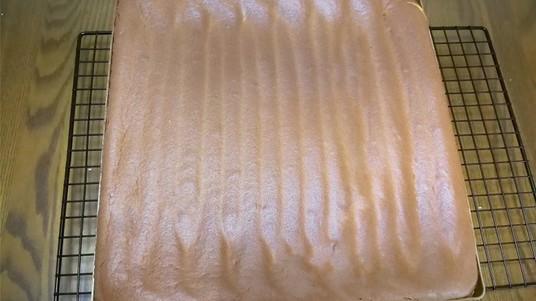 可可旋风卷,烤好取出稍微晾凉,取出用脱模刀在模具周围划一圈,使蛋糕与模具分离。下面铺油纸倒扣到板子上晾凉。(我是反卷所以可可面没怎么刮平,要是正卷的一定要刮平一点。)
