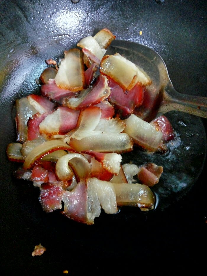 蕨菜炒腊肉,先将腊肉下锅炒出香味,煸出油来。
