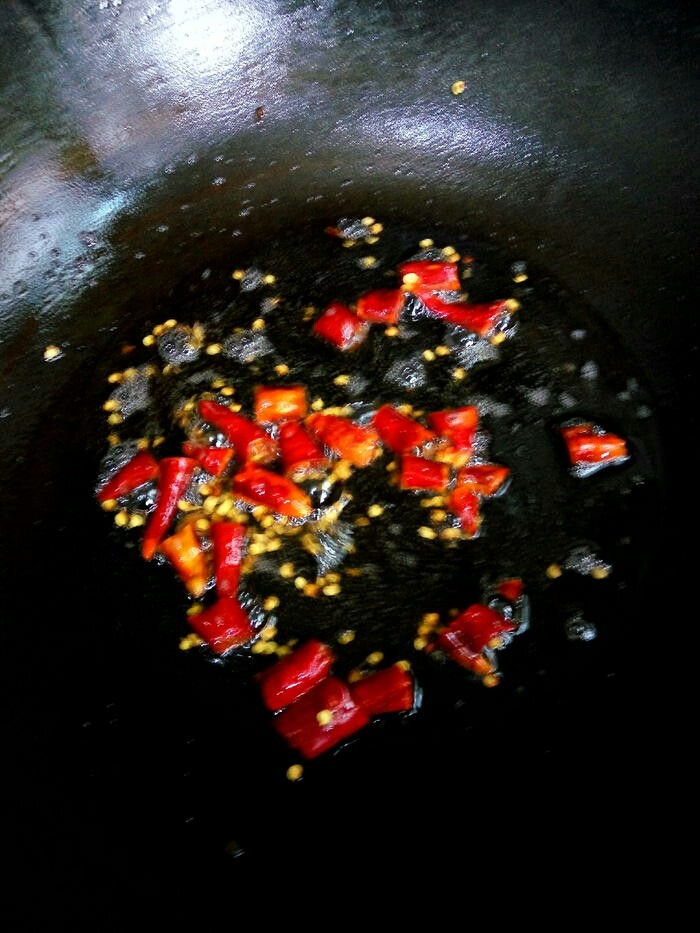 蕨菜炒腊肉,将腊肉捞出,下干椒节到锅里用腊肉油将干椒节煸炒出椒香味。