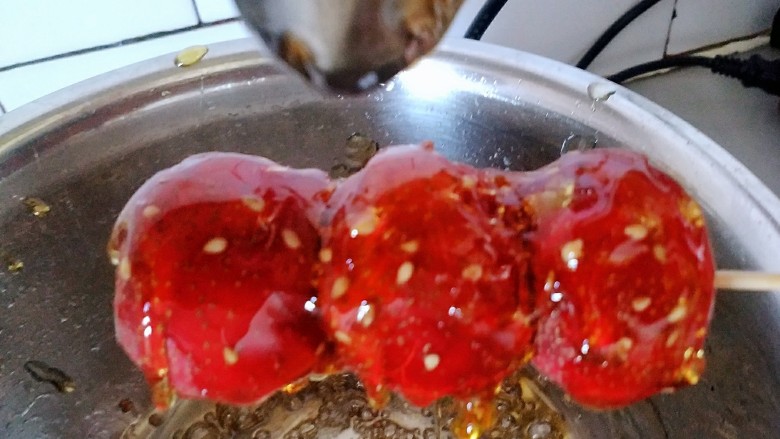 冰糖葫芦,熬好的糖撒上芝麻,把熬好的糖浇在糖葫芦上即可